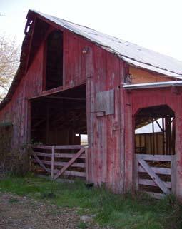 An old red barn with wooden gates across broad openings.