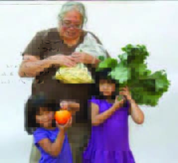 A woman and two young girls hold examples of fresh produce from a Veggie RX program.