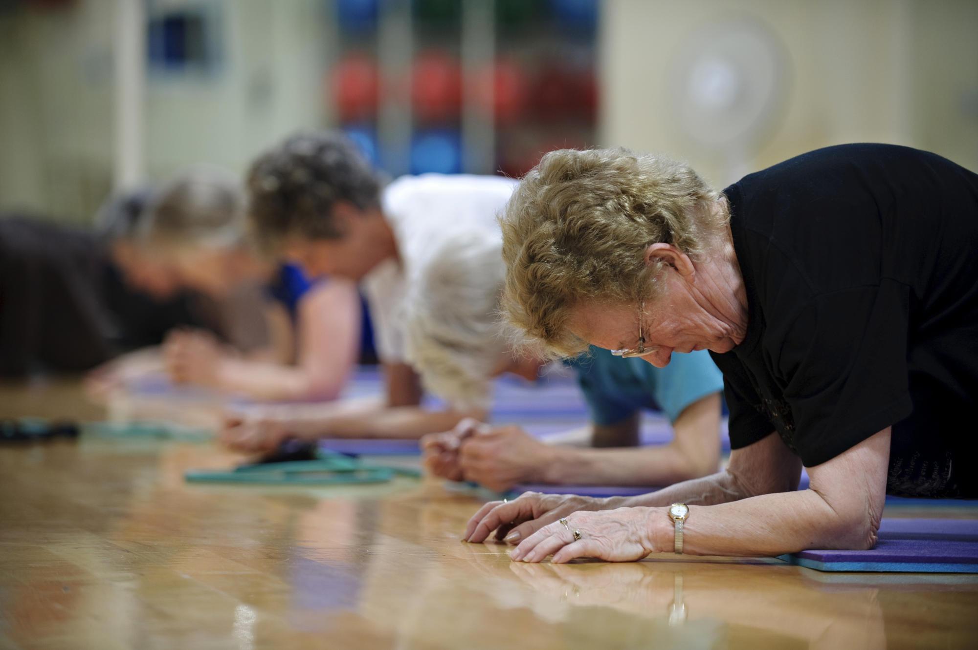 women doing planks on exercise mats in a gym