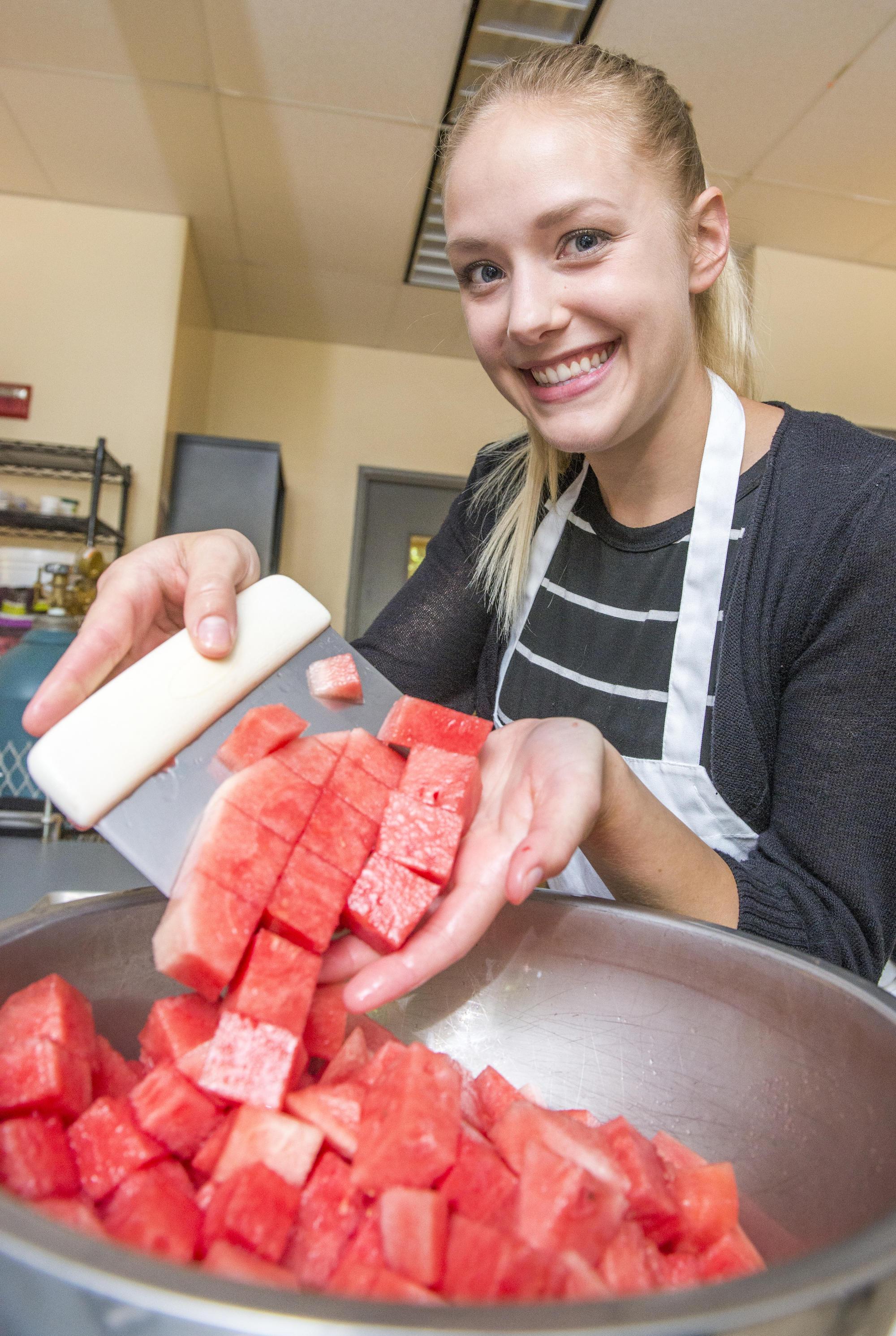 Student cutting watermelon and putting in a bowl