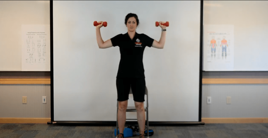 woman holding her arms out to the side with dumbbells in hands