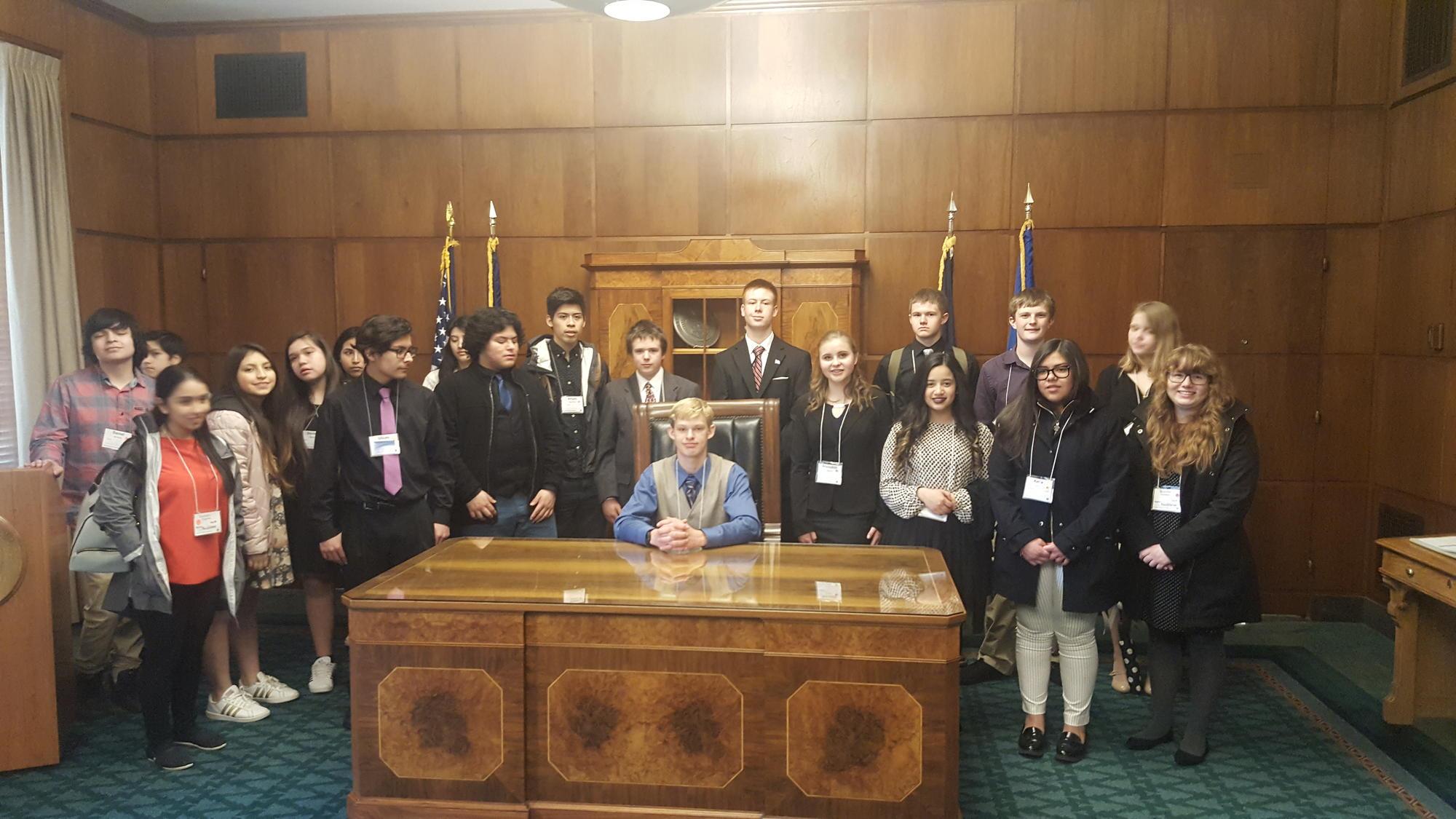 Youth gather at the Oregon Governor's large, elegant wood desk.