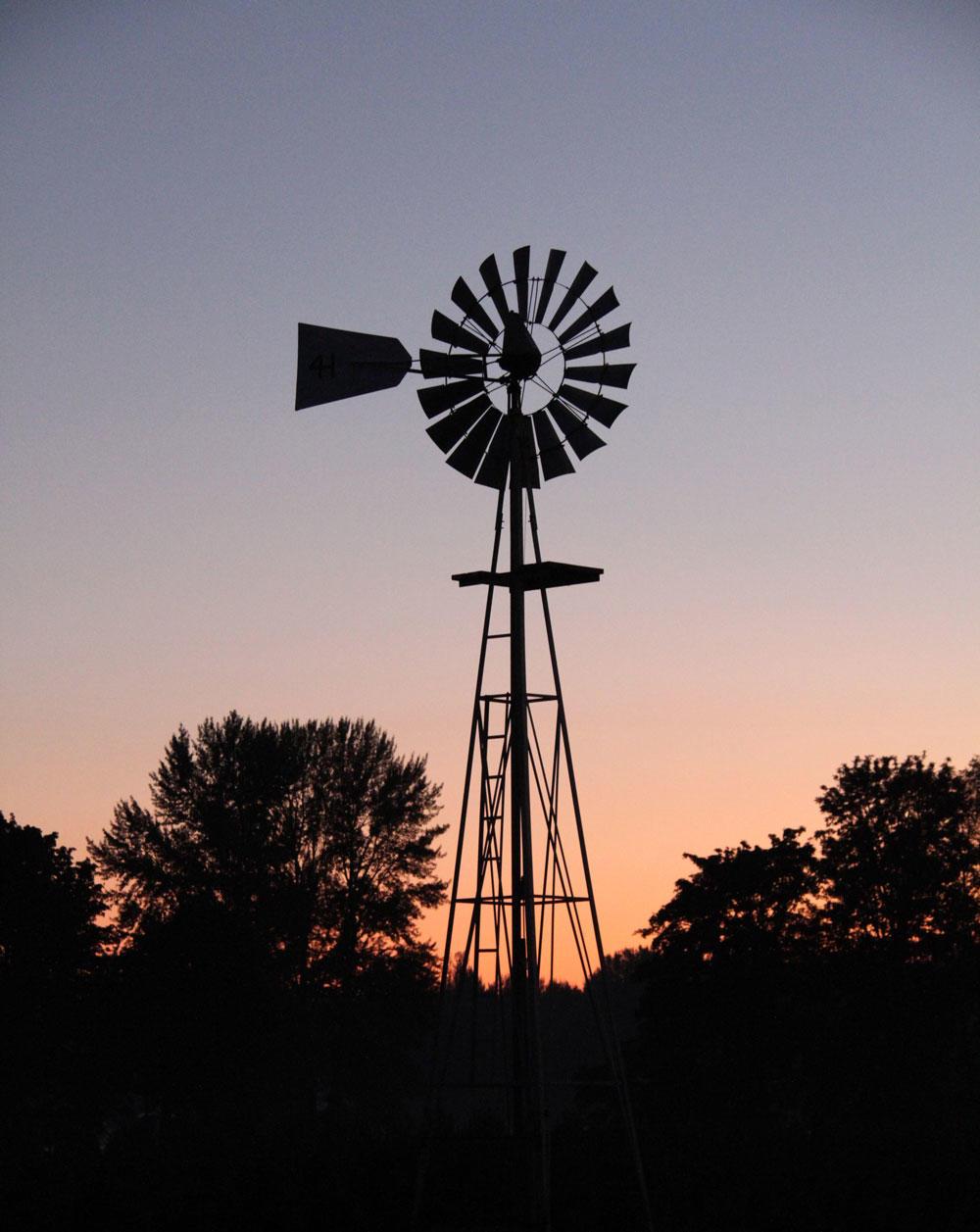 The silhouette of an Oregon farm's windmill is visible against the sky.