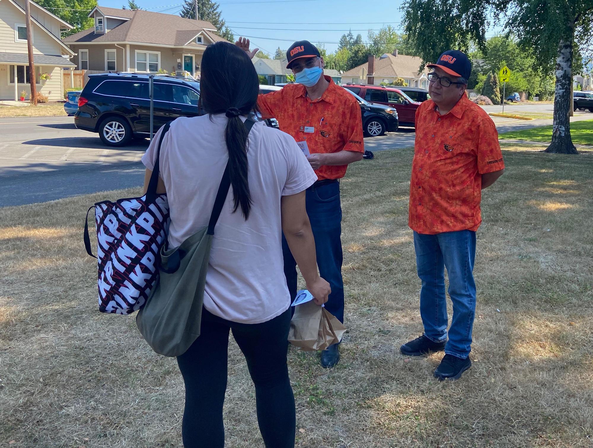 OSU Extension's Jaime Guillen (left) and Rafael Palacios talk to a Newberg resident about a vaccine clinic scheduled for