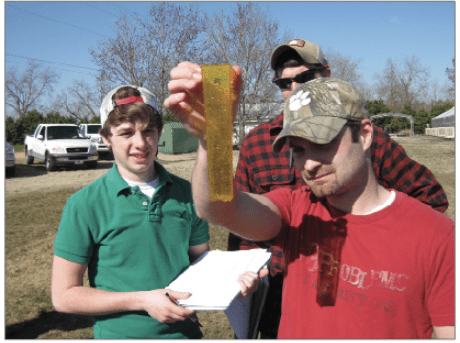 four people looking at a rain gauge