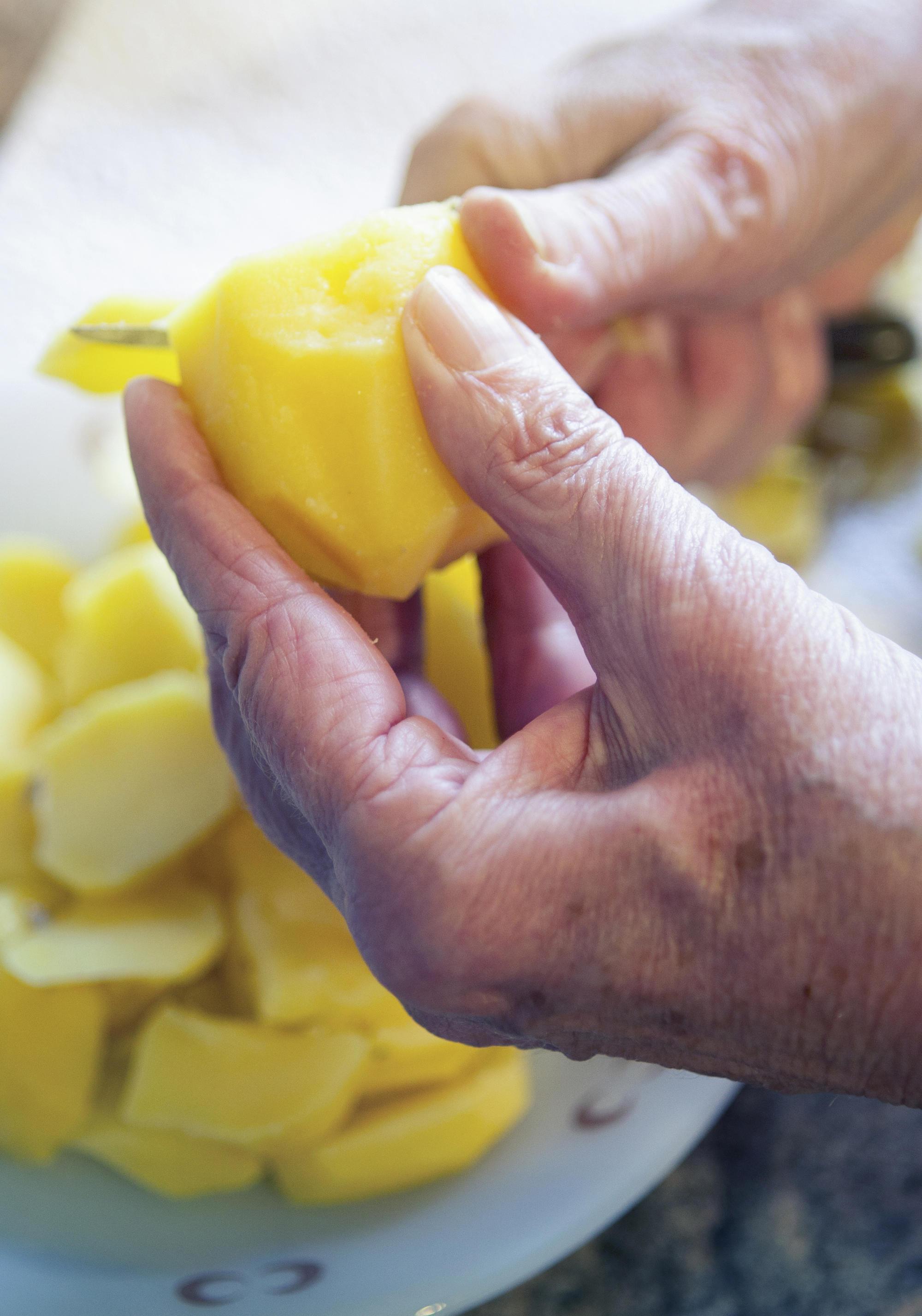 older hands slicing potato