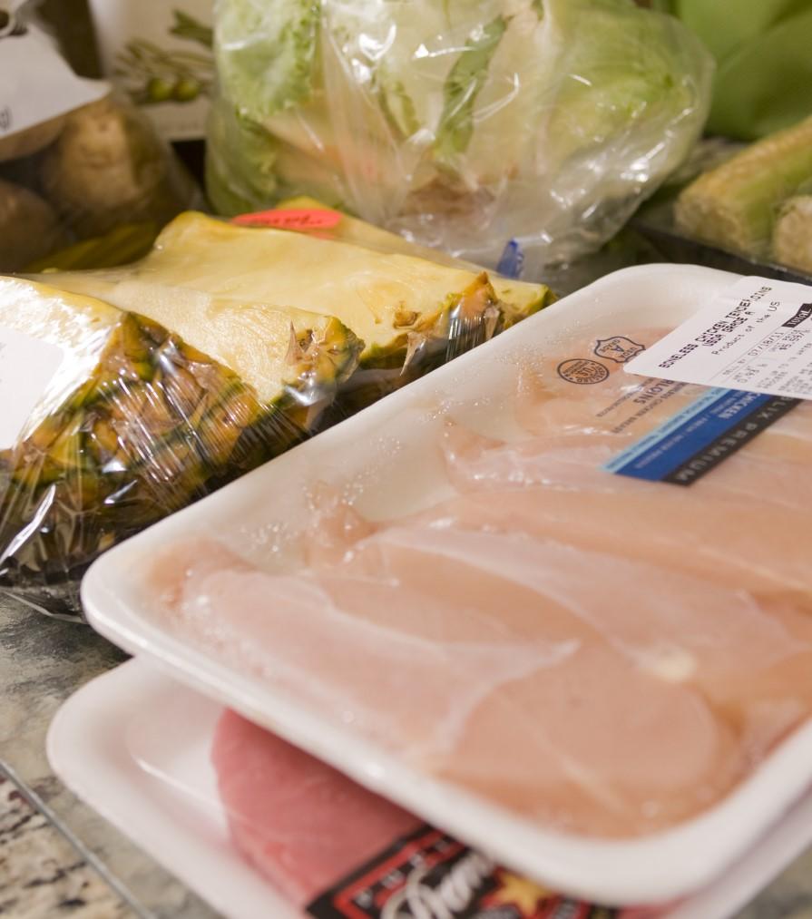 Raw chicken and fruit and vegetables on counter