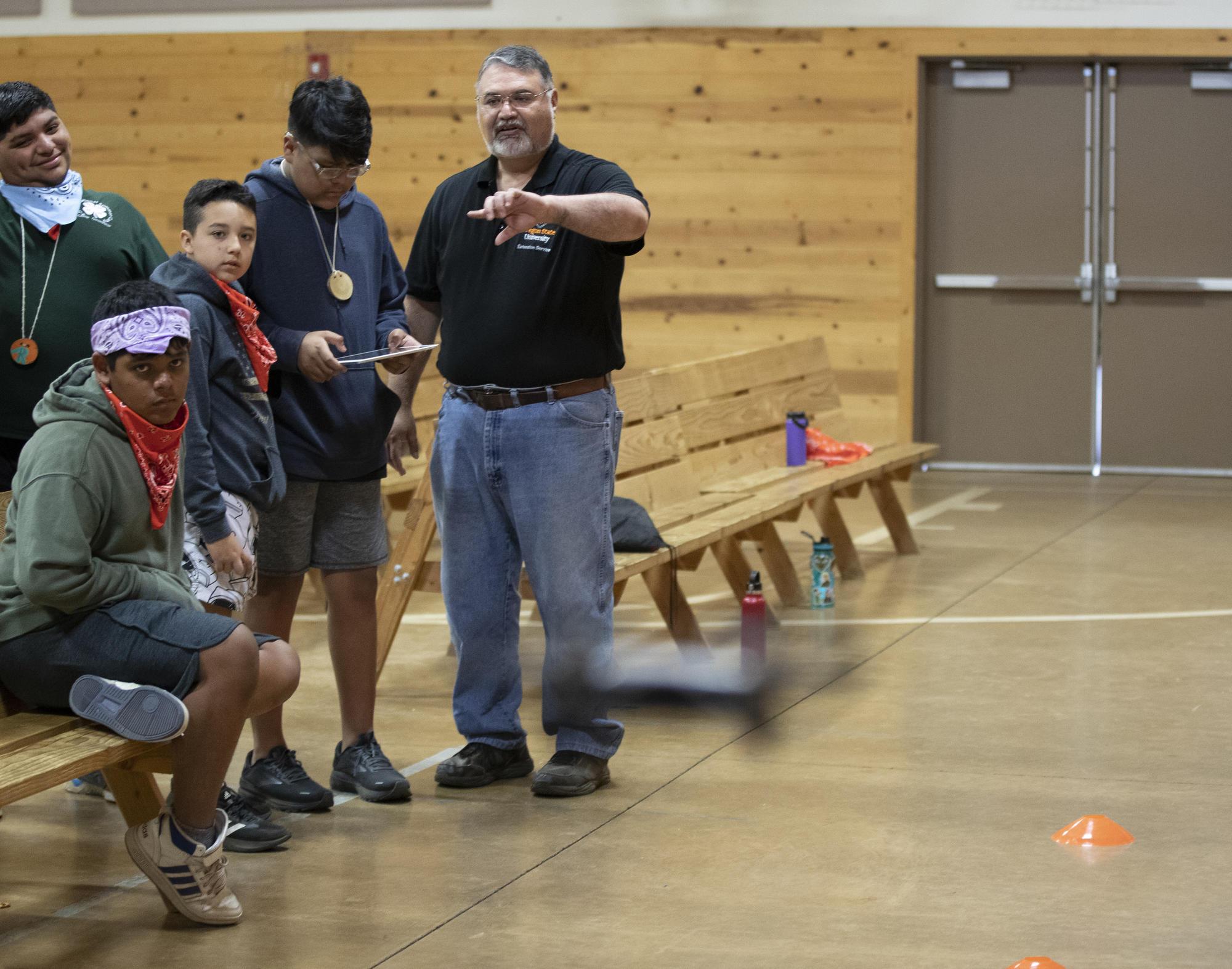 Four 4-H youth looking on as being taught about drones