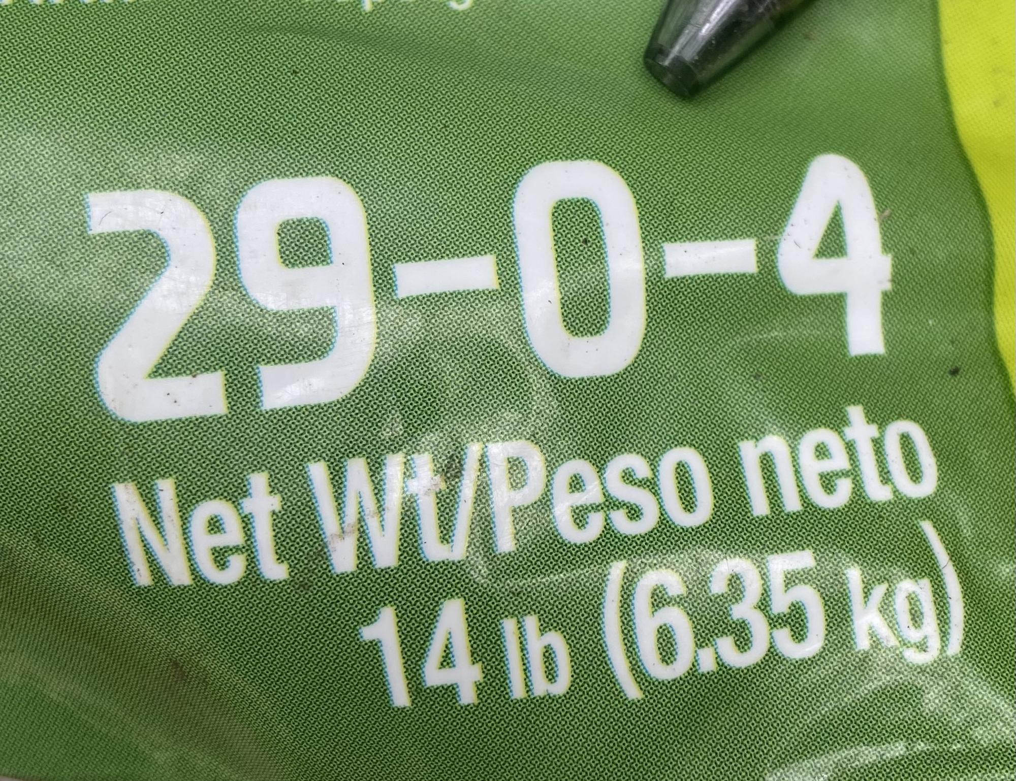 Closeup photo of a green plastic fertilizer bag showing the NPK ratio and net weight in white text.