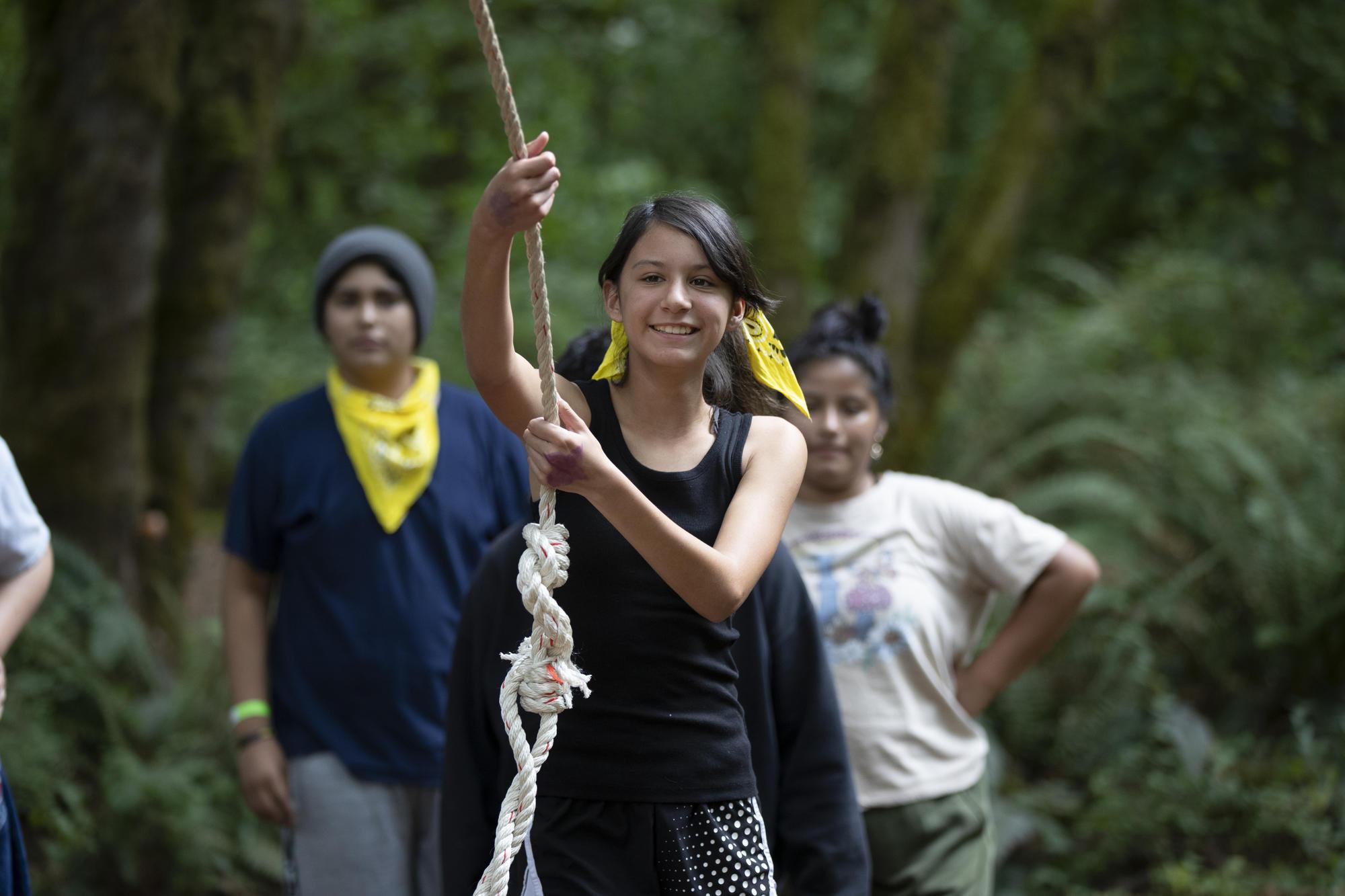 Hispanic youth grabs rope swing