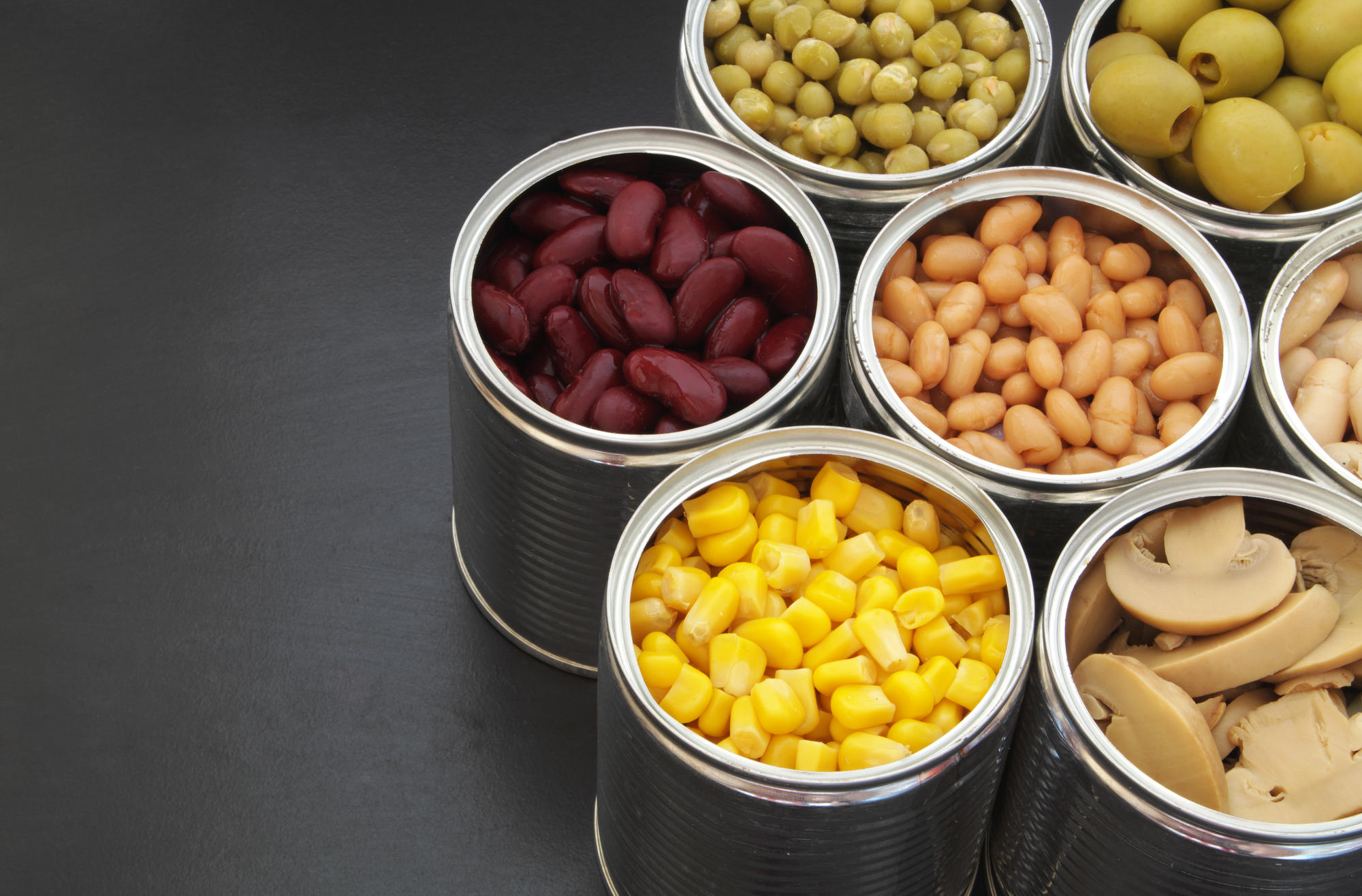 Metal cans of corn, beans, olives, mushrooms, and peas.