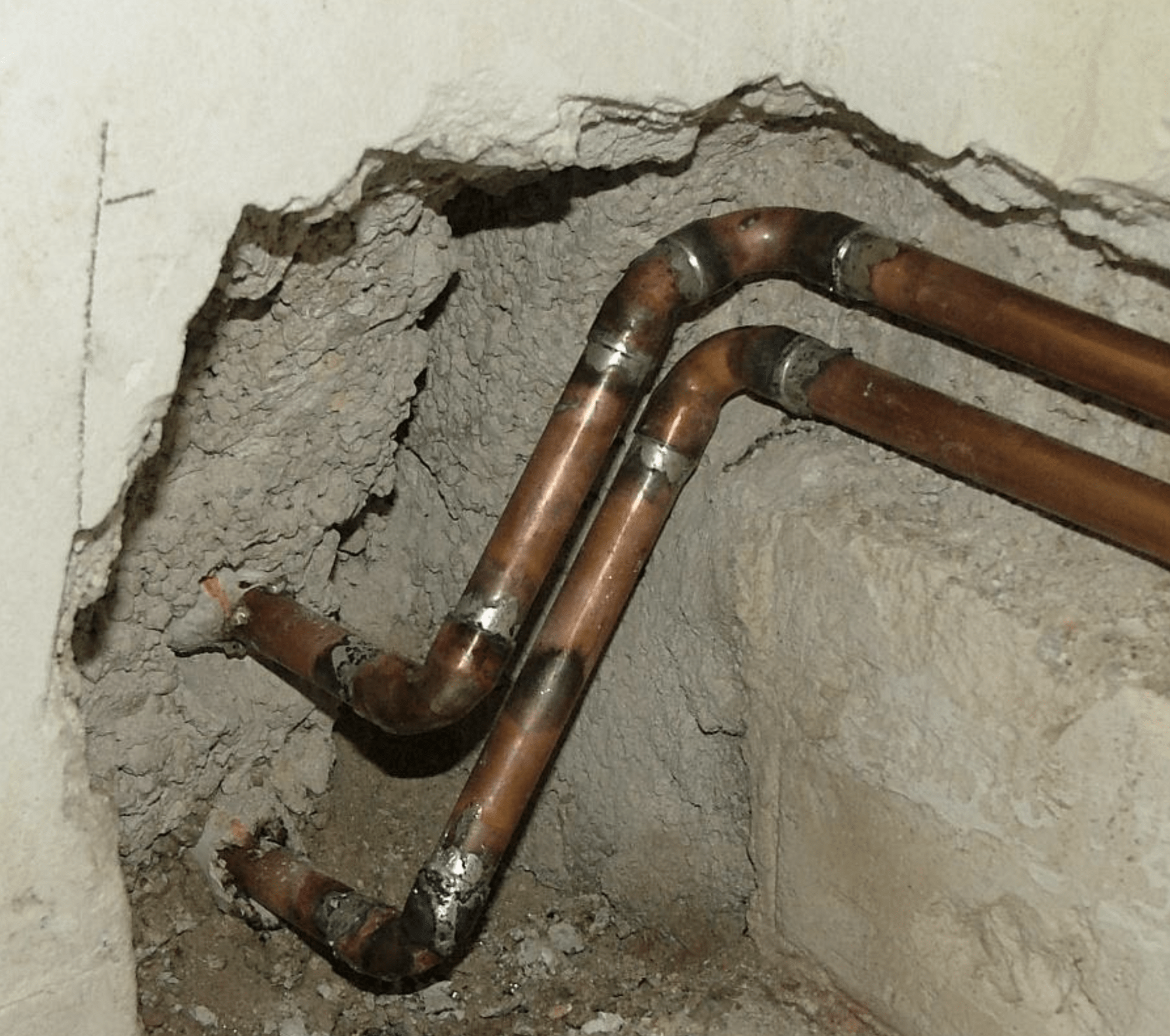 copper pipes with lead solder running along concrete wall