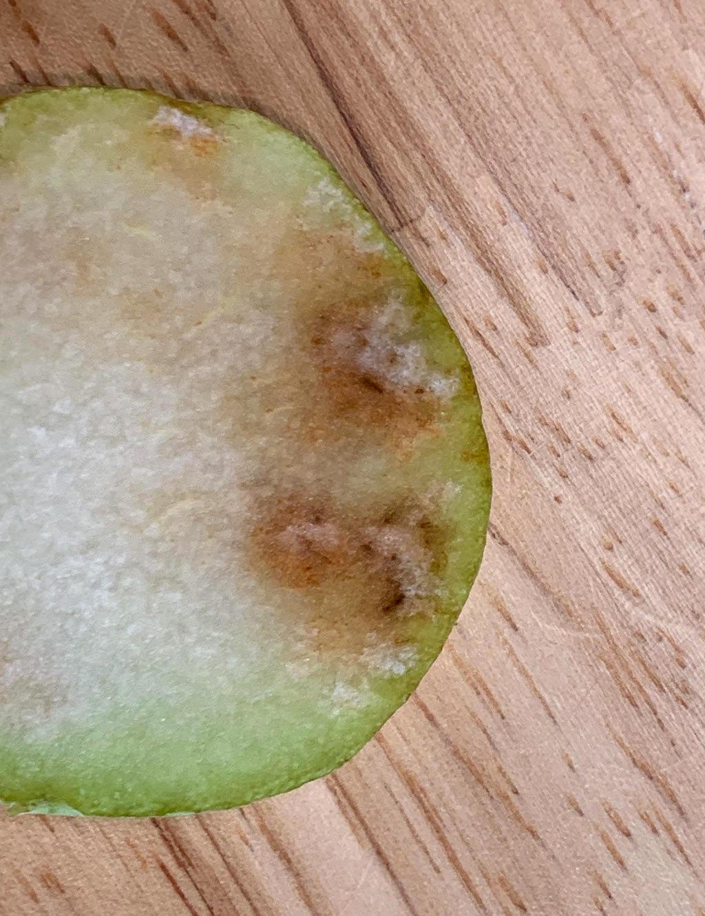pear with top sliced off, exposing icky brown spots along edge of skin