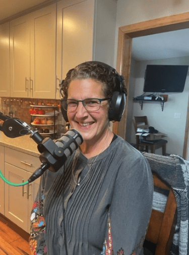 Person in kitchen with headphones on standing in front of a microphone