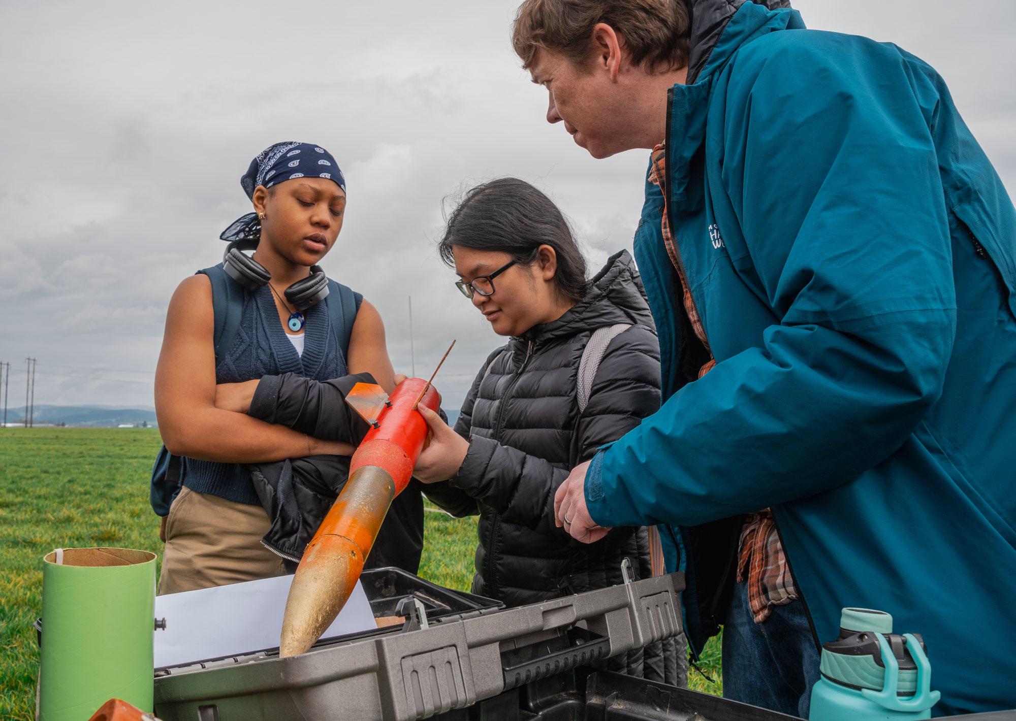 Nikki Truong (middle), a leader of the David Douglas High School Rocket Club, which is affiliated with OSu Extension 4-H, inspects a rocket prior to launch in Hillsboro.