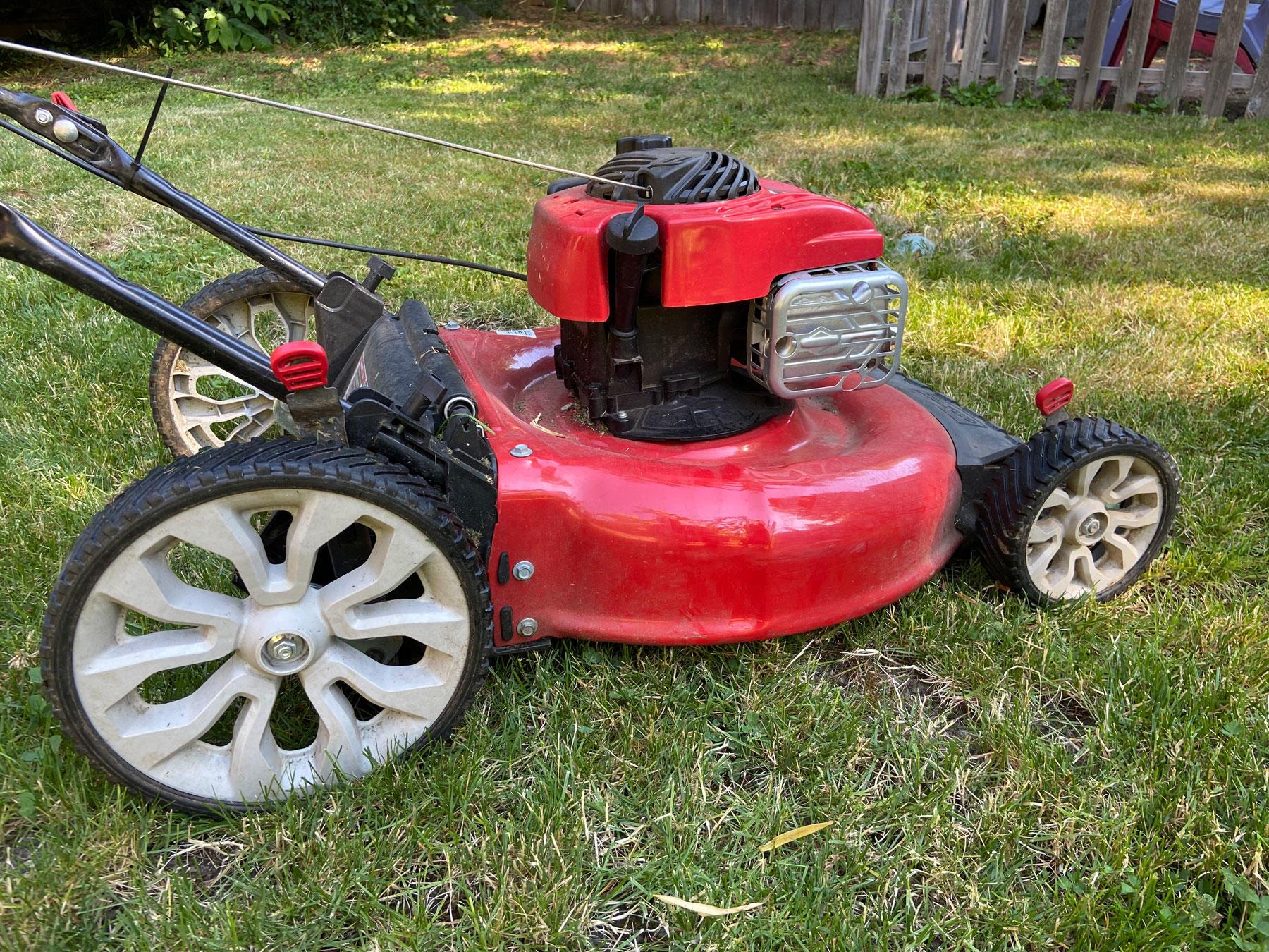 A red lawn mower sitting on fresh-cut green grass.