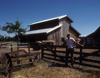 man at wood gate with barn beyond
