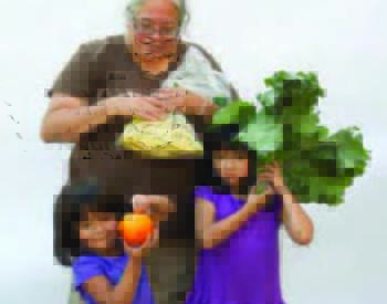 A woman and two young girls hold examples of fresh produce from a Veggie RX program.