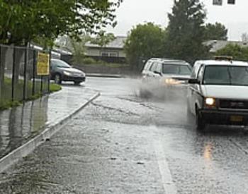 cars driving through standing water on a road