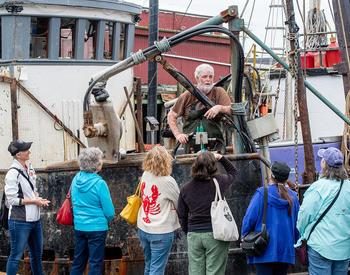 A group of people talks with a fisherman during a Shop at the Dock tour in Garibaldi.