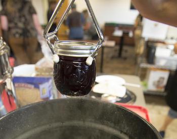 A jar lifter is used to lift a jar of jam out of a boiling water canner.