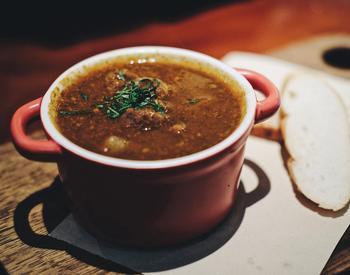 A bowl of soup with a slice of bread alongside.