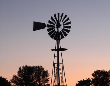 The silhouette of an Oregon farm's windmill is visible against the sky.