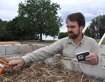 Nick Andrews reads the temperature of a bin of compost that's part of a research project.