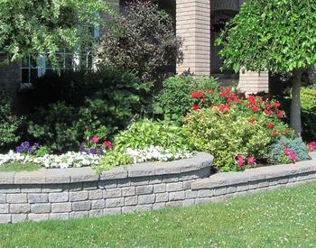 block landscape wall with flower bed behind and lawn in front