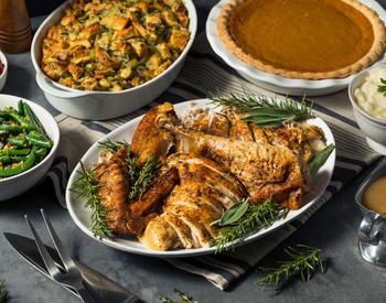 A plate of sliced turkey, surrounded by other holiday dishes.