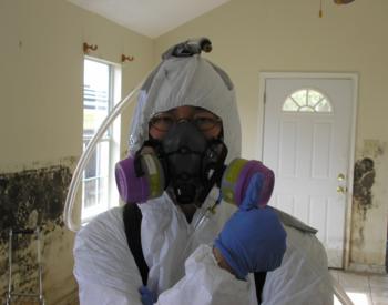 A person in a hazmat suit performing mold abatement.