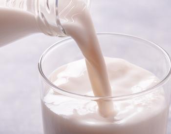 Milk being poured into a glass cup.