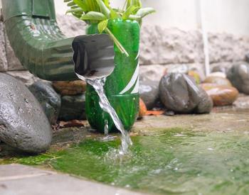 Water pouring from a rain gutter onto a mossy residential driveway.