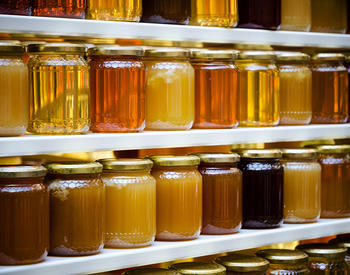 Jars of honey on shelves at a farmers market.