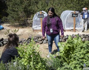 Latina community members talk in a growing garden.