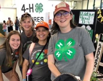 4-H staff and volunteers gather for group photo in front of 4-H booth